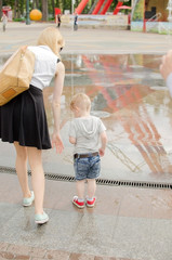 baby boy is walking in hte park with his mother