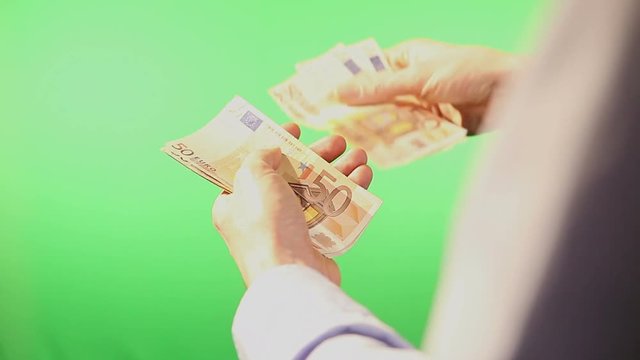 Close up of hands counting various european euro notes over green background.