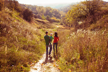 Obraz premium Look from behind at a family walking around the autumn hill