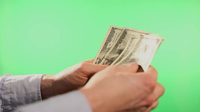 Close up of hands counting various united states dollar notes over green background.