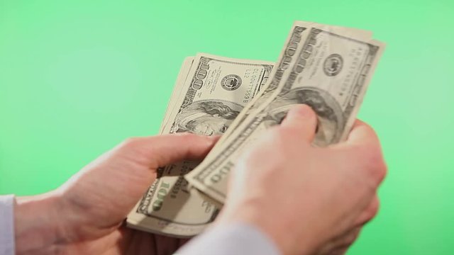 Close up of hands counting various united states dollar notes over green background.