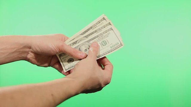 Close up of hands counting various united states dollar notes over green background