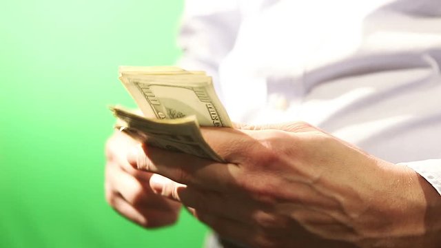 Close of hands counting American Dollar bills. Filmed from close up and in isolation behind a green screen. 