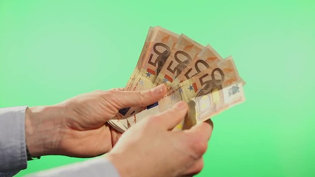 Counting and spreading out Euro banknotes in fifties. Filmed behind a green isolated screen and in close up.