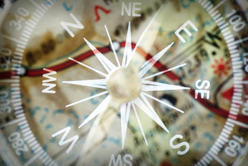 Detail of a magnetic compass on the background of the blurred image of the geographical map
