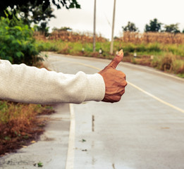 hand and hitchhiking sign on street