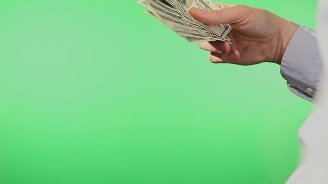 A pair of hands fanning American Dollar Bills. Filmed behind a green, isolated screen. 