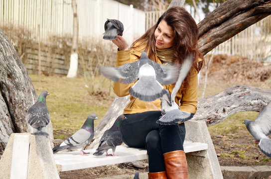 beautiful girl feeding pigeons in the park