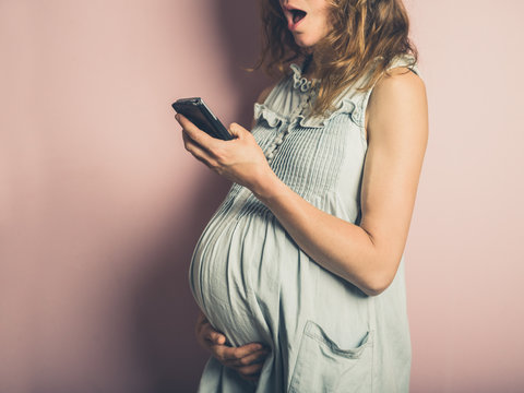 Surprised pregnant woman with cell phone