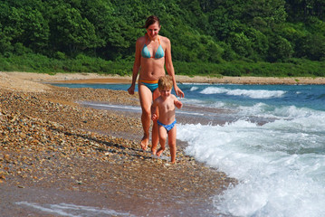 happy family of mother with kid running on the sea beach