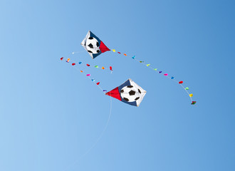 flying kite with soccer-ball symbol over blue sky background
