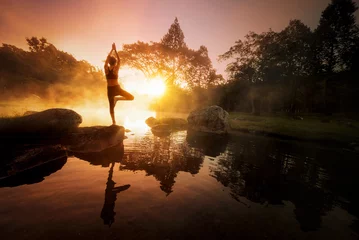 Fototapeten Young woman meditating , yoga by the lake. © weerasak