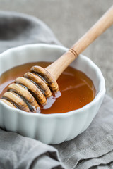 Schale mit Honig und einem Honiglöffel auf einem alten Holzuntergrund