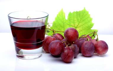 Farm drinks. Red rose grapes bunch, glass cup with red natural organic house wine, and autumn grapes leaves isolated on white background.