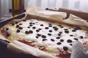 Fototapeta premium Tasty Homemade Pepperoni Pizza with Black Olives and Mozarrella Cheese in Baking Sheet, Toned Image