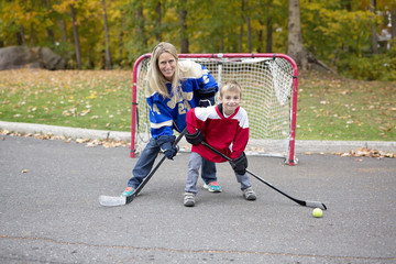 portrait of happy child play hockey outside with mother