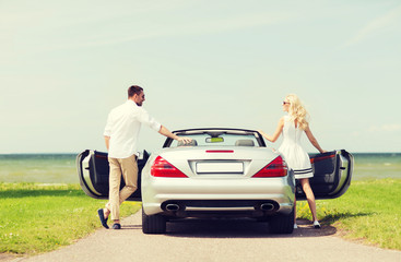 happy man and woman near cabriolet car at sea