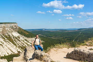 Tourists posing against the backdrop of table mountain Besh-Kosh and the valley of Aslam Dere. Medieval town Chufut-Kale, Bakhchisaray, Crimea