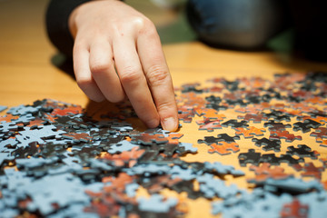 Hand of young girl assembling jigsaw puzzle (color toned image)