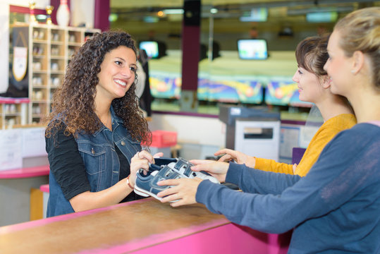 women renting bowling shoes at a bowling alley