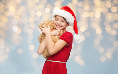 smiling girl in santa helper hat with teddy bear