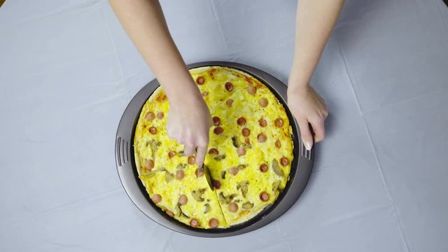 Cutting piece of pizza from roundshape baking tray 4K