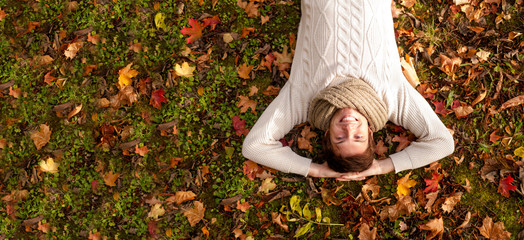 smiling young man lying on ground in autumn park