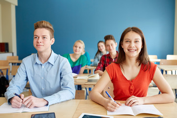 happy students with notebooks at school