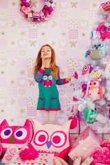 Obraz na płótnie Canvas Girl in green dress stands behind a toy Christmas tree
