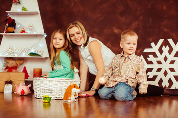 Happy children and their mother play on the wooden floor