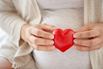 close up of pregnant woman with red heart