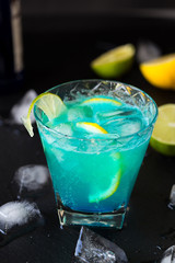 Blue Lagoon Cocktail with Lemon and Ice on Dark Background.