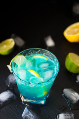 Blue Lagoon Cocktail with Lime, Lemon and Ice on Dark Background, Top View