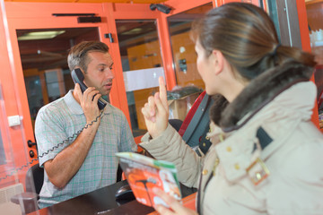 Woman trying to get attention of man in ticket office