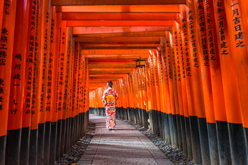 Women in kimono stand at Red Torii gates in Fushimi Inari shrine, one of famous landmarks in Kyoto,...
