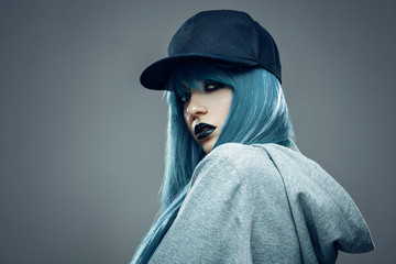 Young womanwith cyan color hair in hoodie and cap