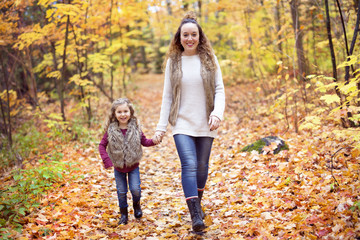 Young mother playing with her daughter in autumn park