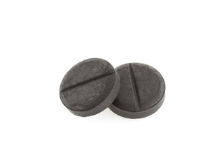 Active black charcoal pills isolated on white background