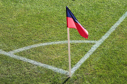 A red and blue flag at one corner of football stadium and soccer corner of a soccer field