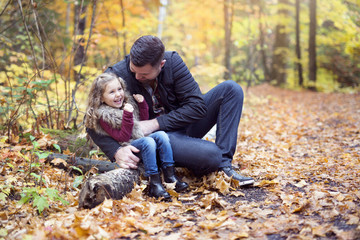 Little adorable girl with happy father in autumn park outdoors