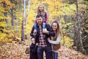 Fototapeta premium Family of four enjoying golden leaves in autumn park