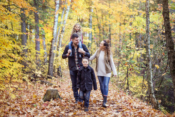 Naklejka na ściany i meble Family of four enjoying golden leaves in autumn park