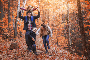 Naklejka premium Family of four enjoying golden leaves in autumn park