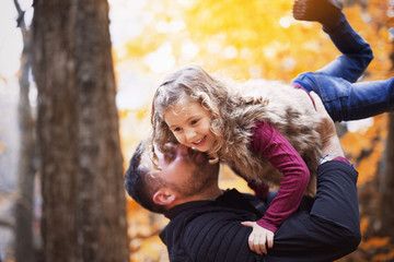 Little adorable girl with happy father in autumn park outdoors