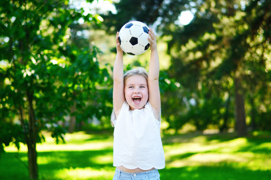 Adorable little soccer fan cheering on hot summer day at park