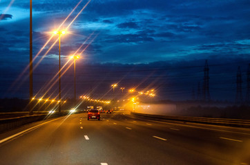 Fototapeta na wymiar Road at dusk. Lights oncoming cars.