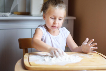 Fototapeta premium Adorable little girl making the dough for pasta