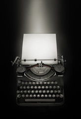 Ancient typewriter against black background. Light effect over white page
