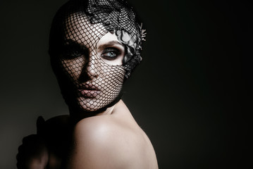 Fashion portrait of a beautiful woman in a black veil on her face. Isolated on gray background. Advertising Space