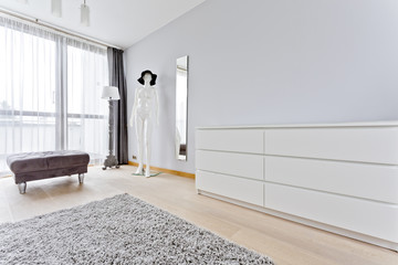 Interior with stylish pouf, simple commode and manikin